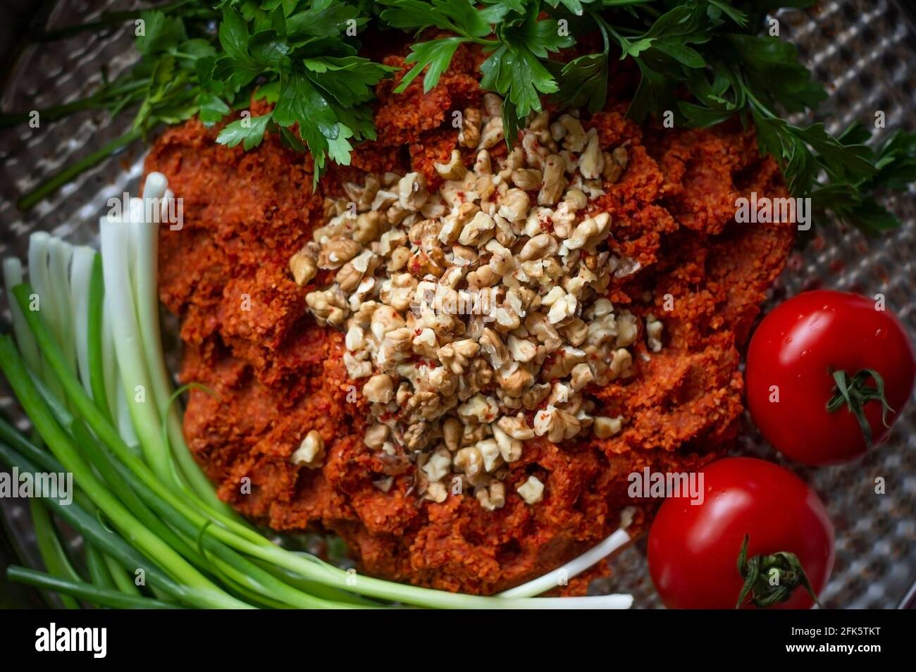 Türkische rohe Fleischbällchen (Cig kofte; ein rohes Fleischgericht) mit Salat, Zwiebeln und Tomaten. Nahaufnahme Stockfoto