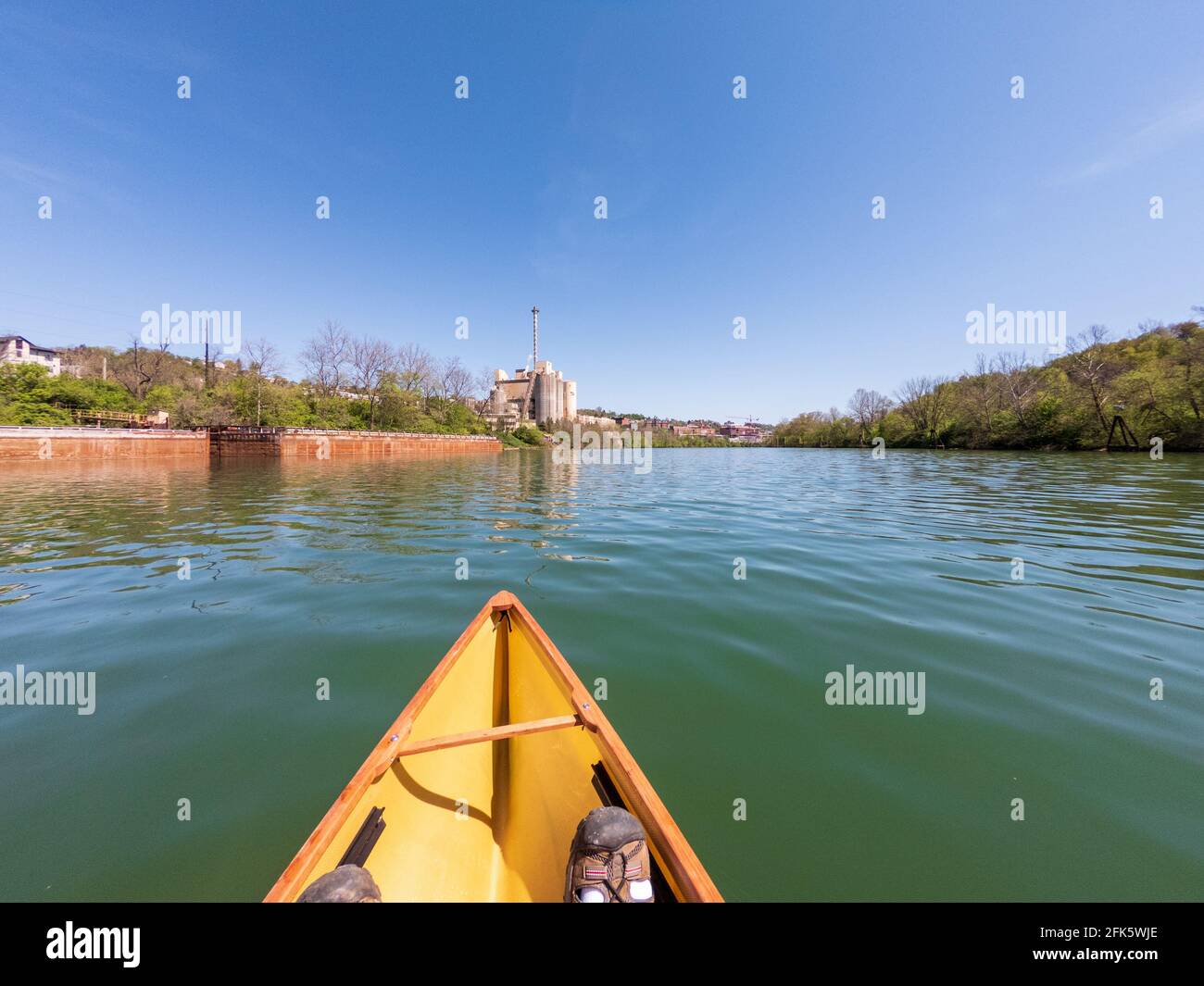 Kaukasischer Mann, der in einem Packkanu den Monongahela-Fluss in Morgantown, West Virginia, hinunter paddelt Stockfoto