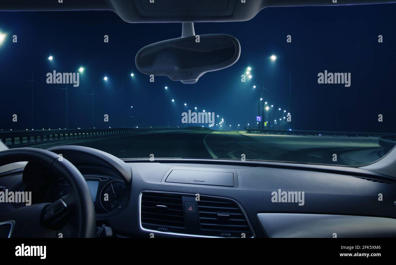 Blick durch die Windschutzscheibe des Autos.Winter Autobahn in der Nacht Glänzt mit Lampen Stockfoto