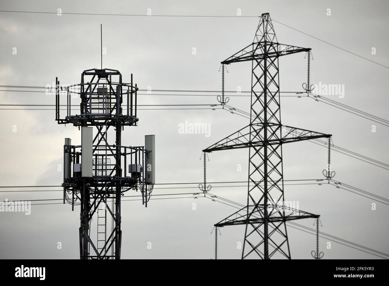Nahaufnahme eines silhouettierten Mobilfunknetzes Telefonmast und Elektrischer Gittermast Stockfoto
