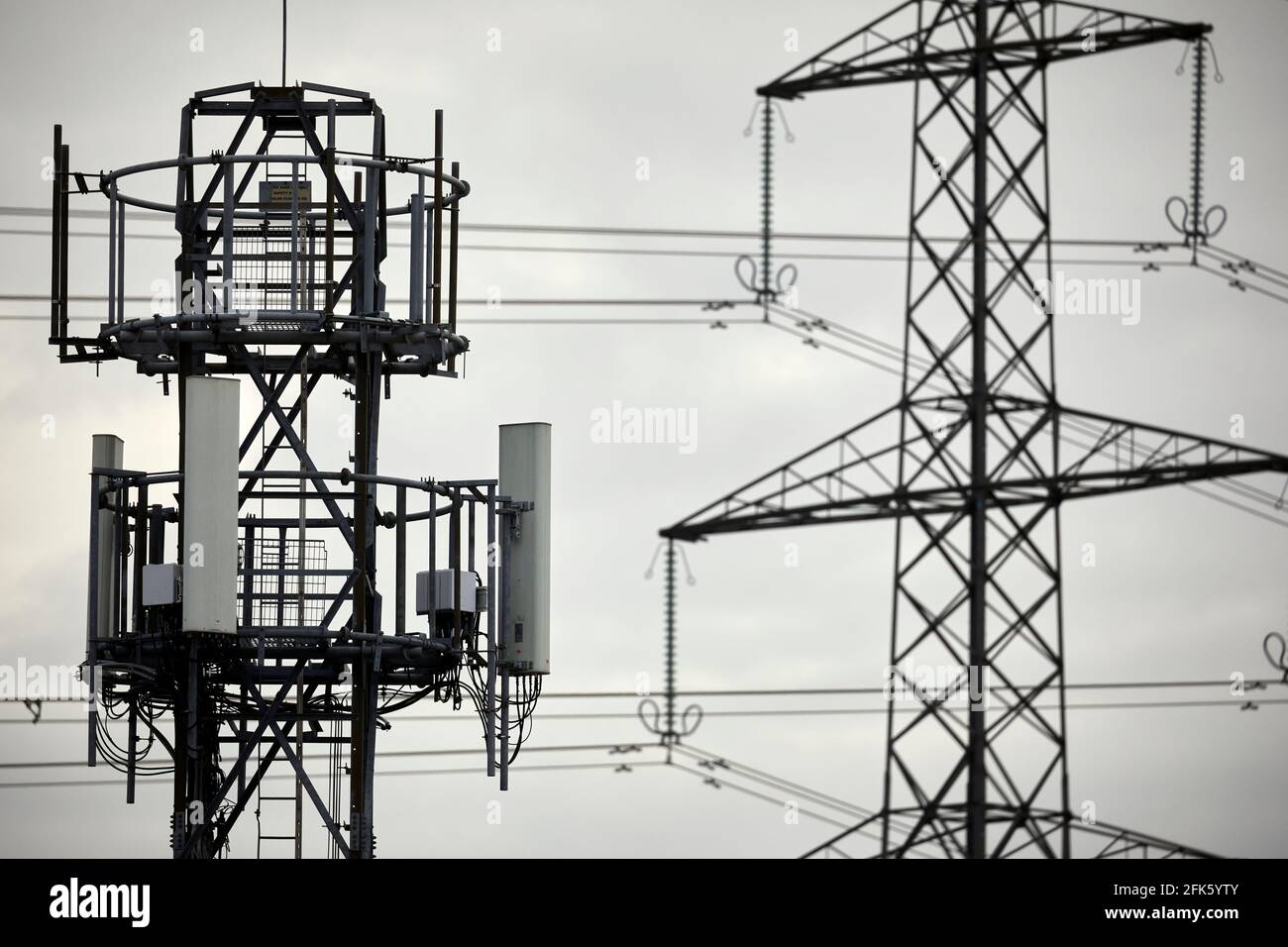 Nahaufnahme eines silhouettierten Mobilfunknetzes Telefonmast und Elektrischer Gittermast Stockfoto