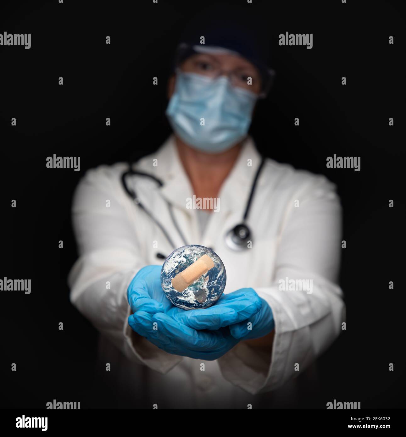 Krankenschwester oder Arzt mit Gesichtsmaske und OP-Handschuhen, die den Planeten Erde mit Bandagen halten. Stockfoto