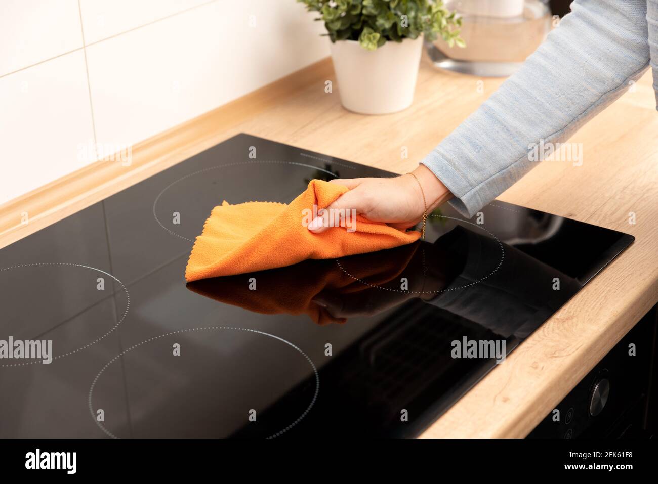 Frau, die Induktionsherd putzt. Moderne Küche mit Induktionskochfeld Stockfoto