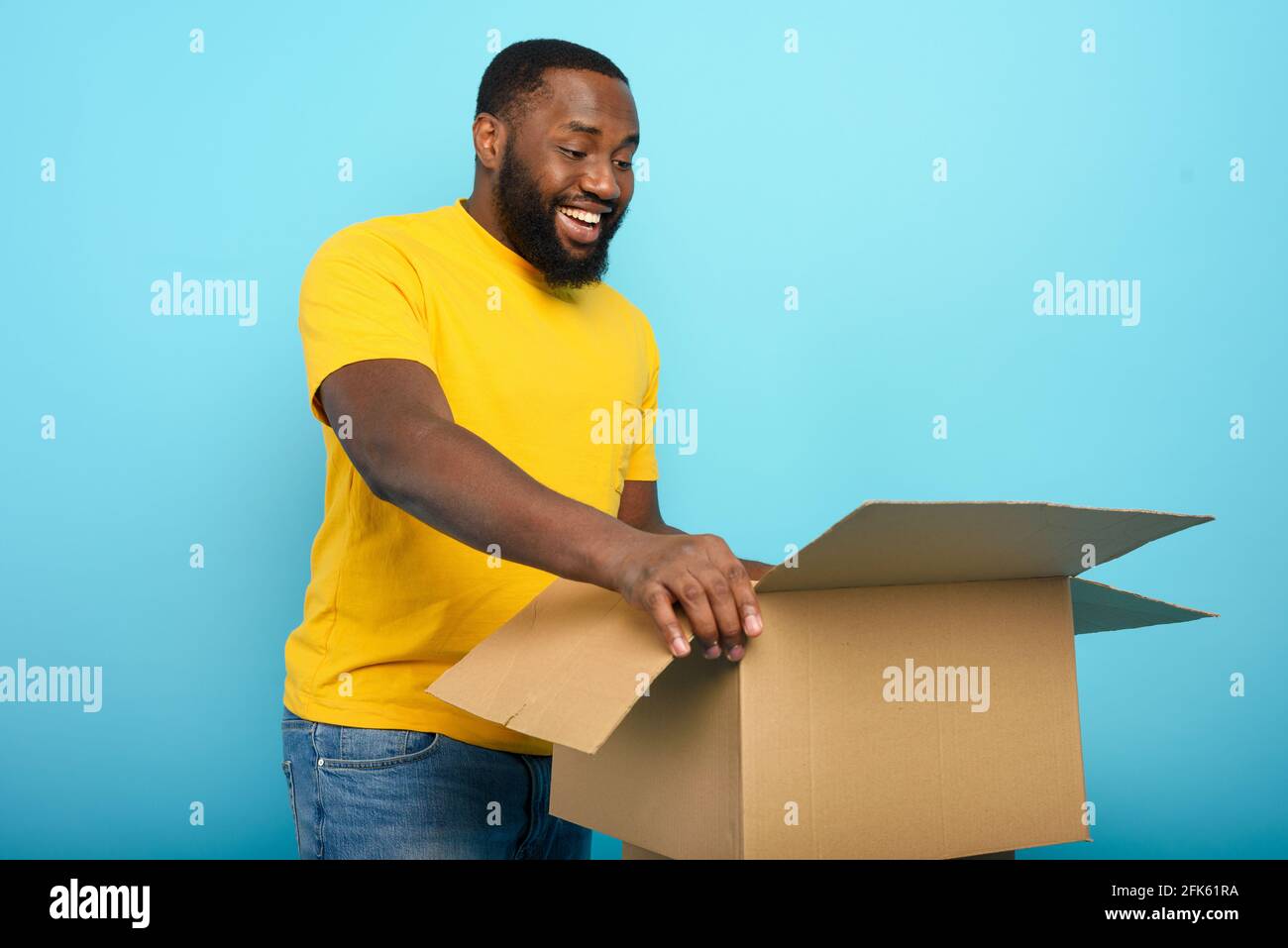 Glücklicher Mann erhält ein Paket von Online-Shop-Bestellung. Happy Expression. Blauer Hintergrund. Stockfoto