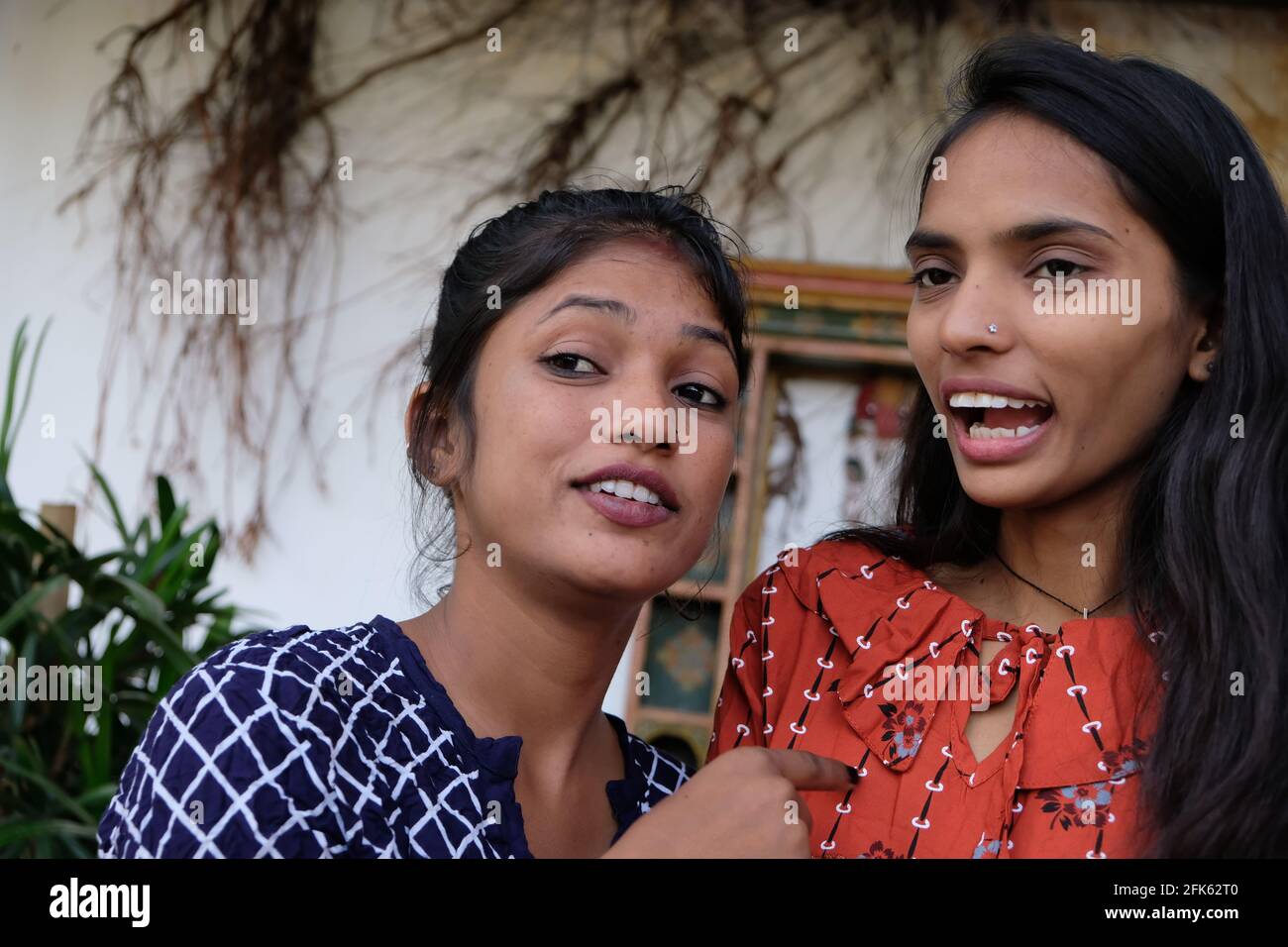 Junge indische Frau erzählt etwas und zeigt auf ihre Freundin Stockfoto