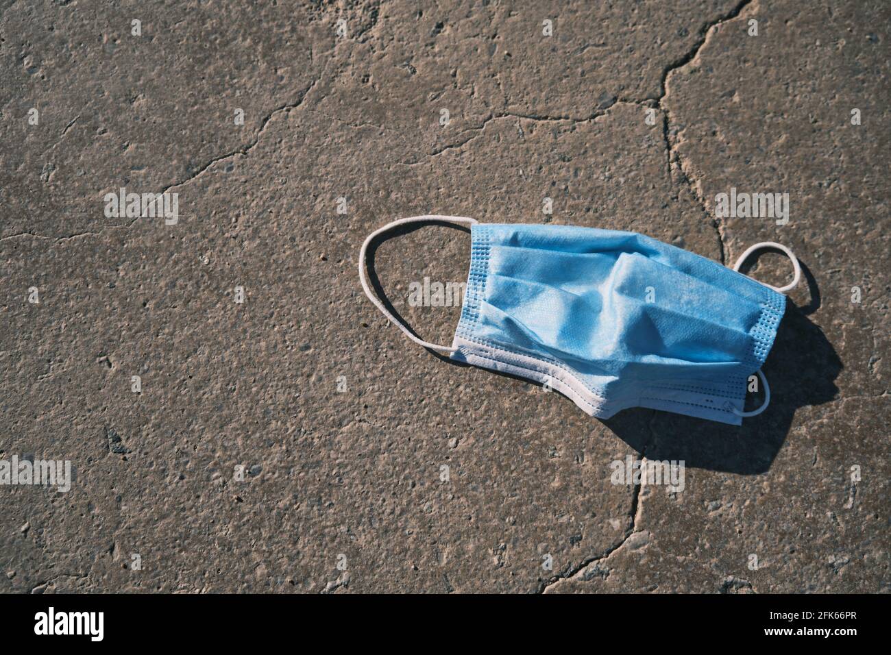 Maske auf einem rissigen Boden nach dem Ende von covid-19, Glück für das Ende von covid-19, virusfreie maskenfreie Feiertage, Ende von covid-19, maskenfreier Strand, nach der Pandemie normales Leben, Impfung Stockfoto