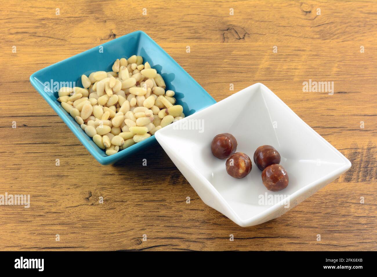 Pine Nuss harte Süßigkeiten in weißen Süßigkeitenschale mit Kiefer Nüsse in einer blauen Snack-Schale Stockfoto