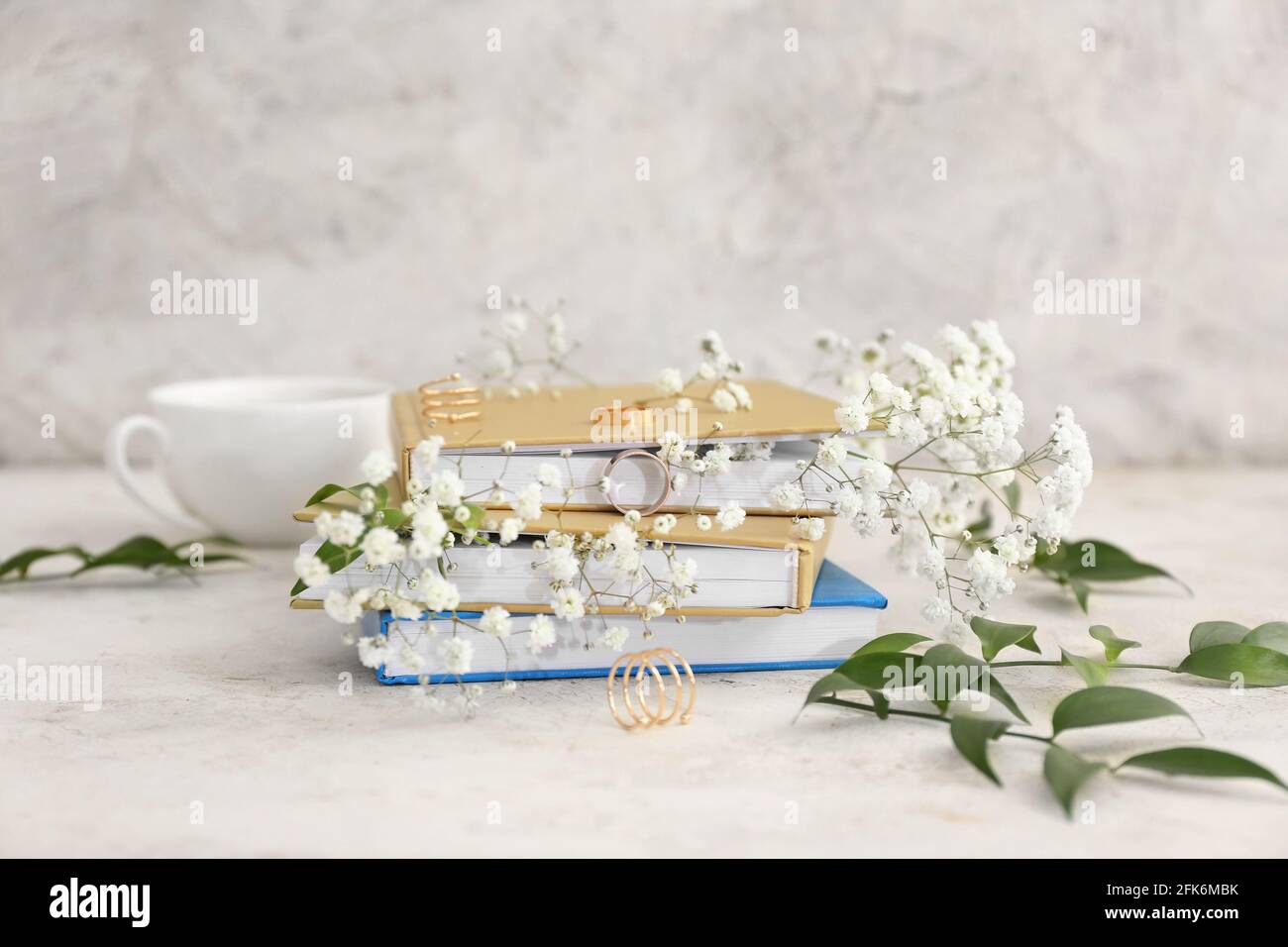 Bücher mit Blumendekor und goldenen Ringen auf grünem Hintergrund Stockfoto