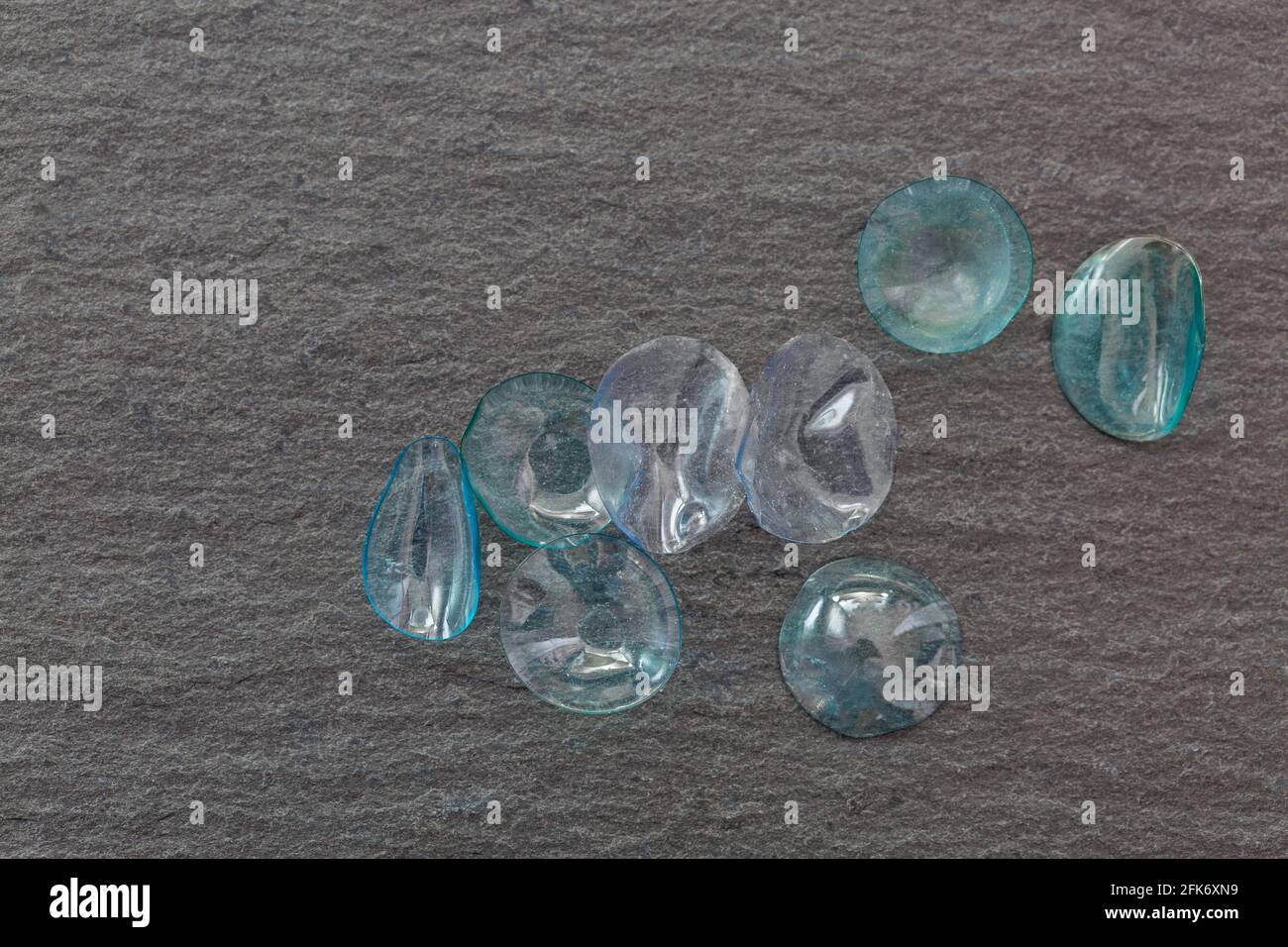 Gruppe von gebrauchten monatlichen Einweg-Kontaktlinsen auf schwarzem Stein Hintergrund. Getrocknete und staubige Kontaktlinse mit Copyspace Stockfoto