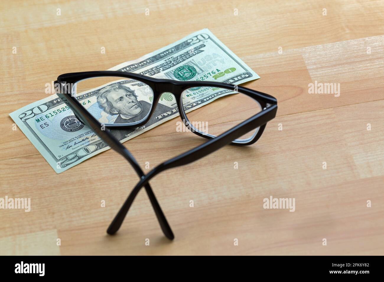 Brille mit schwarzem Rahmen, Augenbrille auf 20-Dollar-Geldschein mit Fokus auf Gesicht, auf Holzhintergrund Stockfoto