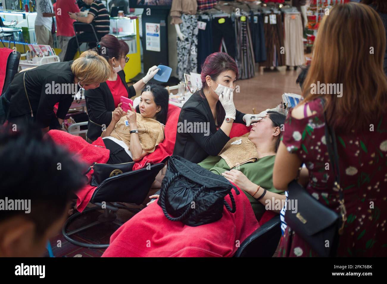 19.11.2017, Singapur, Republik Singapur, Asien - Frauen werden im Schönheitssalon im People's Park Center in Chinatown die Augenbrauen ausgerissen. Stockfoto