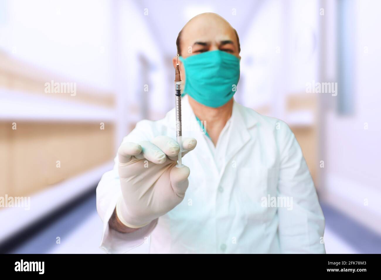 Porträt eines Arztes, der eine Maske trägt, die eine Spritze Covid-19 oder einen Coronavirus-Impfstoff in einem Krankenhaus hält, Pfizer, COVISHIELD und COVAXIN-Dosis für den Patienten zur Steigerung Stockfoto