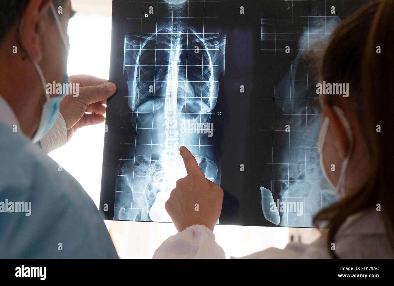 Junge Ärztin mit leitendem Arzt prüft eine Röntgenaufnahme. Konzept der Zusammenarbeit zwischen jungen Ärzten und erfahrenen Ärzten. Stockfoto