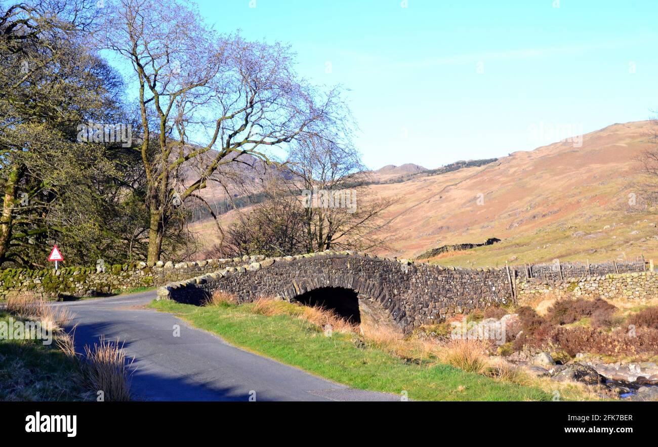 Straße und Brücke über den Fluss Duddon in Cockley Beck, Duddon Valley, Lakes, Cumbria, Großbritannien; Hill Farming Ackern. Stockfoto