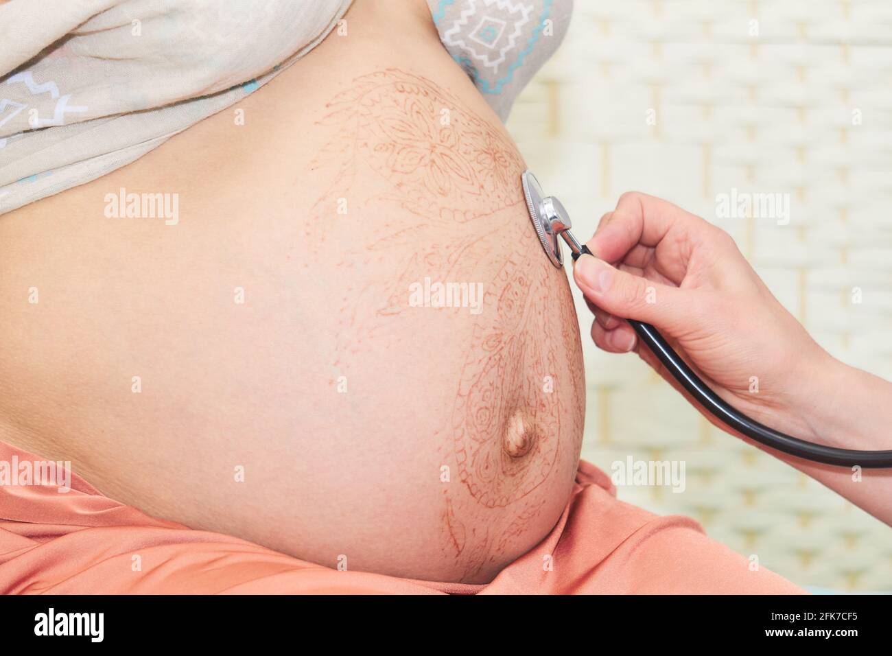 Der Arzt untersucht eine Schwangeren, indem er dem Fötus zuhört Herzschlag mit einem Phonendoskop Stockfoto