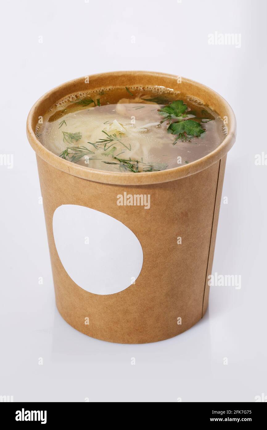 Suppe in einer Tasse recyceltem Papier isoliert auf weißem Hintergrund. Konzept der Bio-Lebensmittelverpackung. Stockfoto