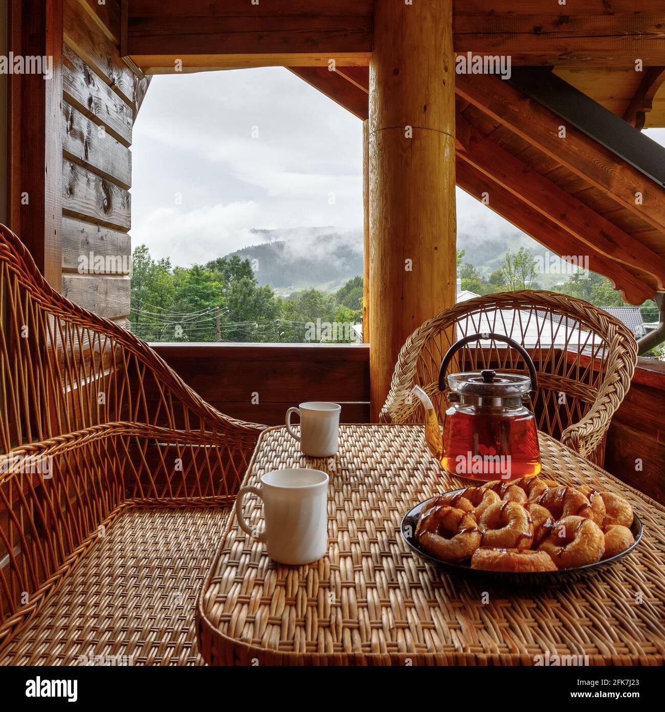 Frühstück auf dem Balkon eines Holzhauses mit Korbmöbeln. Stockfoto