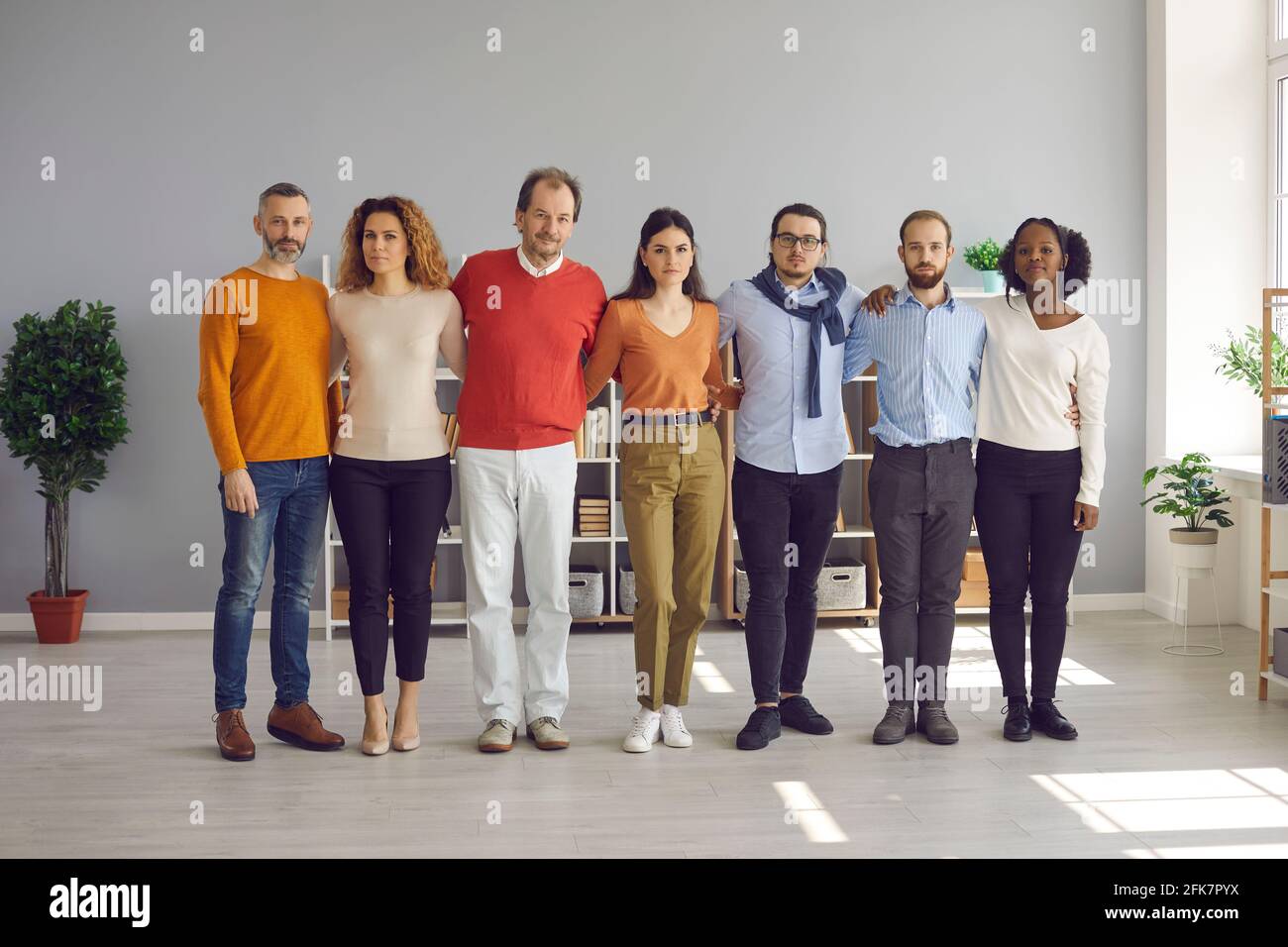 Verschiedene multiethnische Gruppen von Erwachsenen und jungen Menschen umarmen sich stehend In Reihe Stockfoto
