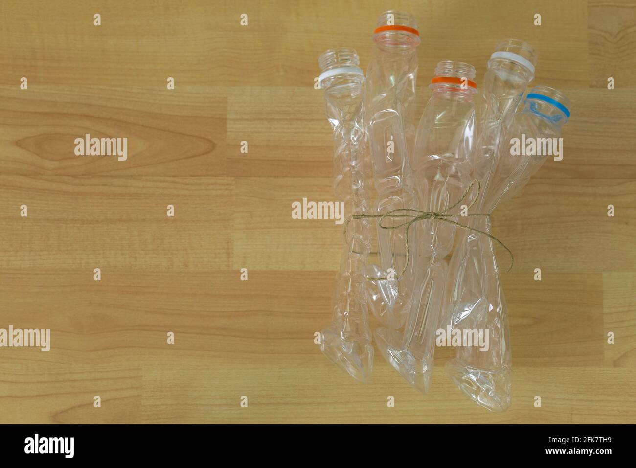 Gruppe leerer, recycelbarer, klarer Kunststoff-Mineralwasser-Flaschen Zusammengebunden auf Holzhintergrund mit Copyspace Stockfoto