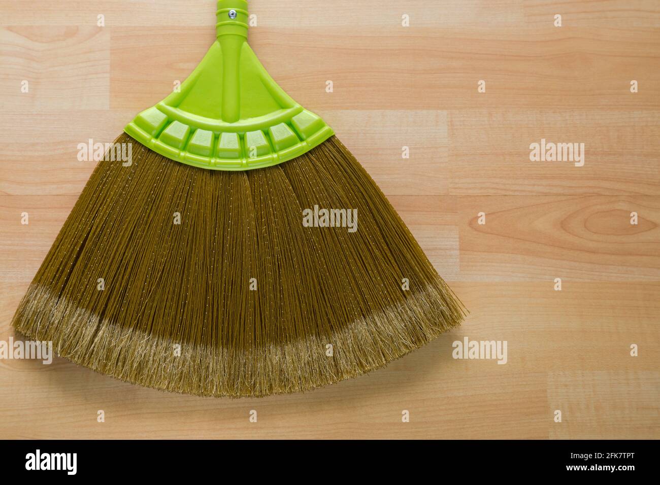 Nahaufnahme des neuen Besen aus synthetischer Nylonfaser mit Grüner Griff auf Holzhintergrund mit Copyspace Stockfoto