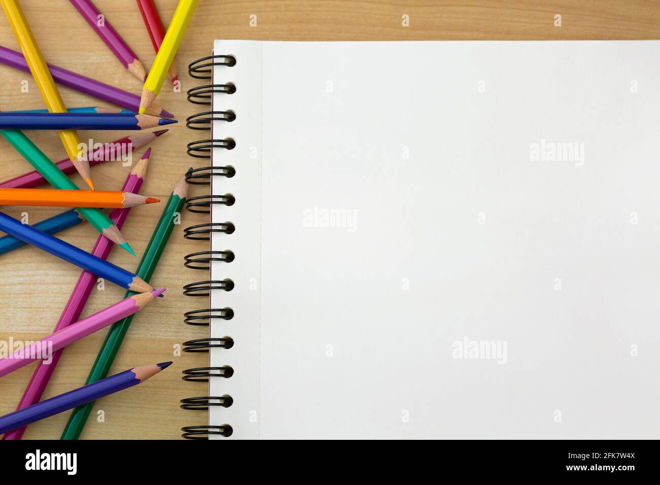 Draufsicht auf Farbstifte neben Skizzenzeichnung Buch auf Holzhintergrund Stockfoto