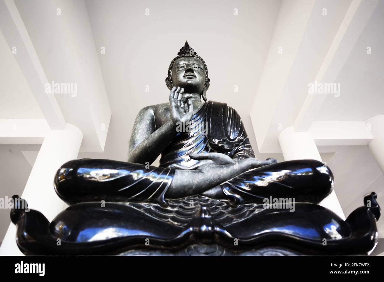 Eine schwarze Buddha-Statue in einem weißen Tempel in Thailand Stockfoto
