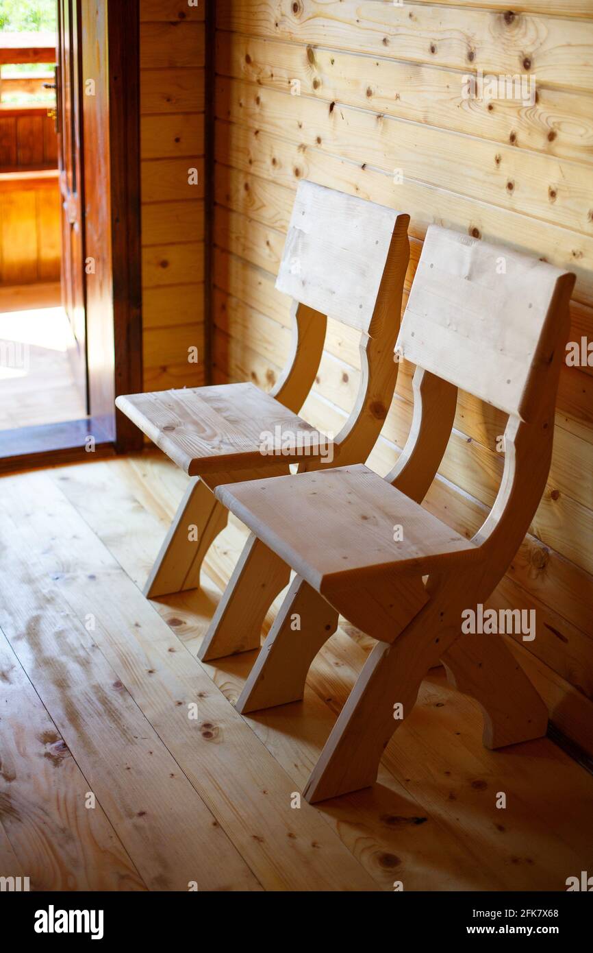 Seitenansicht der kleinen selbstgemachten Holzstühle, die neben der Eingangstür stehen. Stockfoto