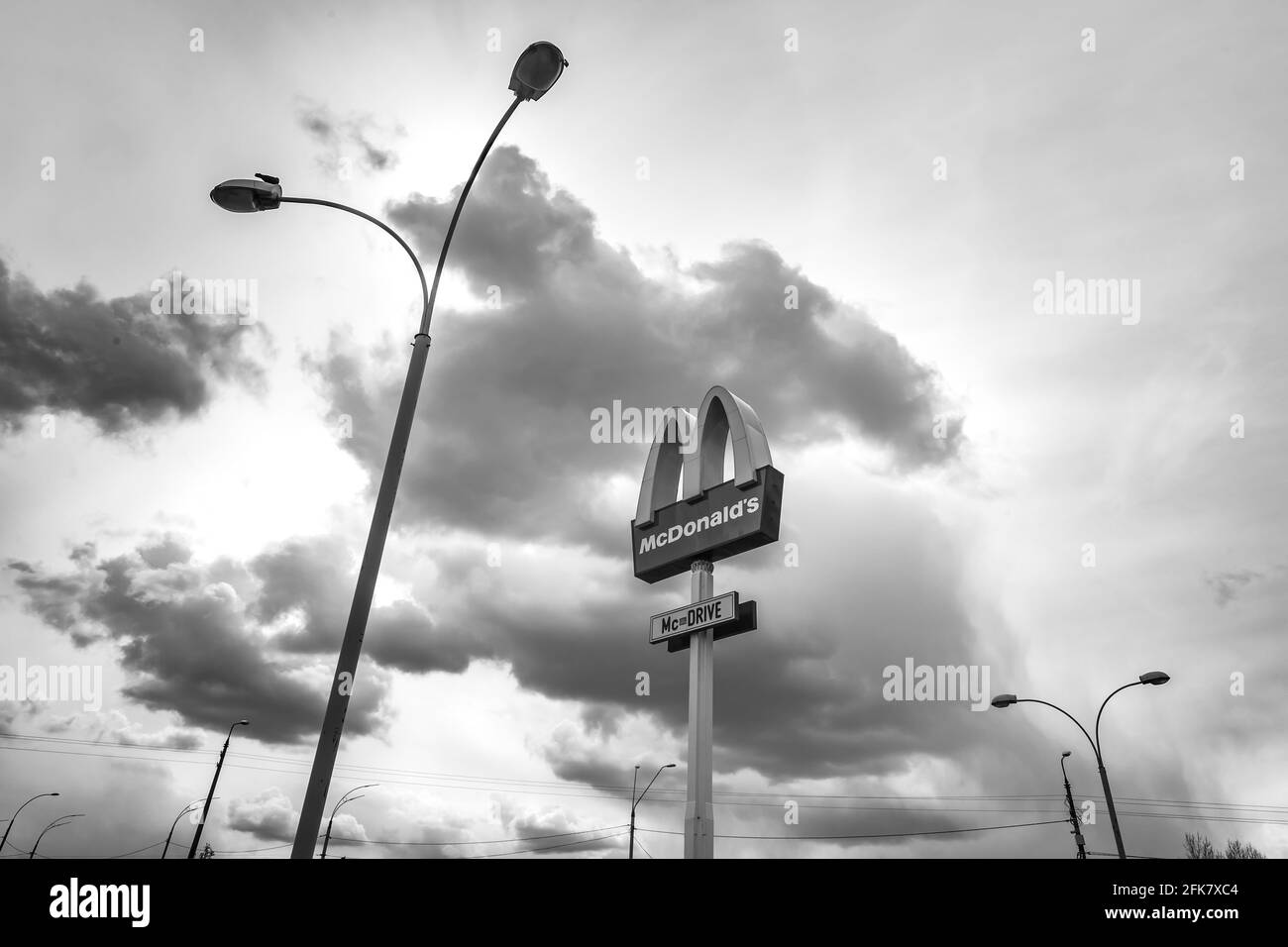 KIEW, UKRAINE - 27. April 2021: Das Logo der globalen Fast-Food-Restaurantkette McDonalds am blauen Himmel mit Wolken Stockfoto