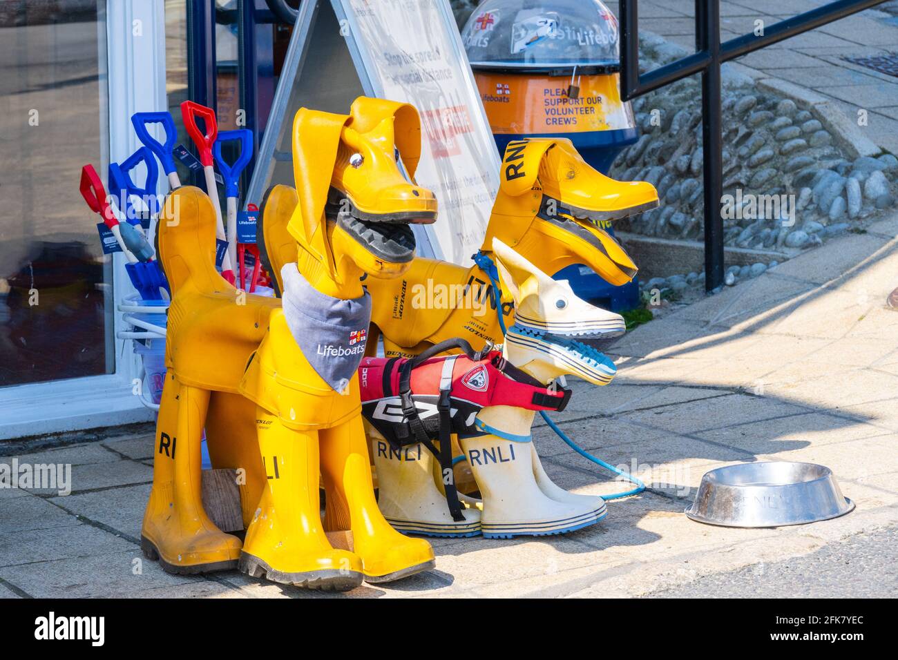 Lyme Regis, Dorset, Großbritannien. April 2021. Wetter in Großbritannien. RNLI Rettungsboot Hundefamilie aus gelben Gummikrüppen vor dem RNLI Charity Shop bei Lyme Regis an einem sonnigen Tag. Wohltätigkeitsorganisationen leiden unter wiederholten Sperren und Einschränkungen für Besucher. Kredit: Celia McMahon/Alamy Live Nachrichten Stockfoto