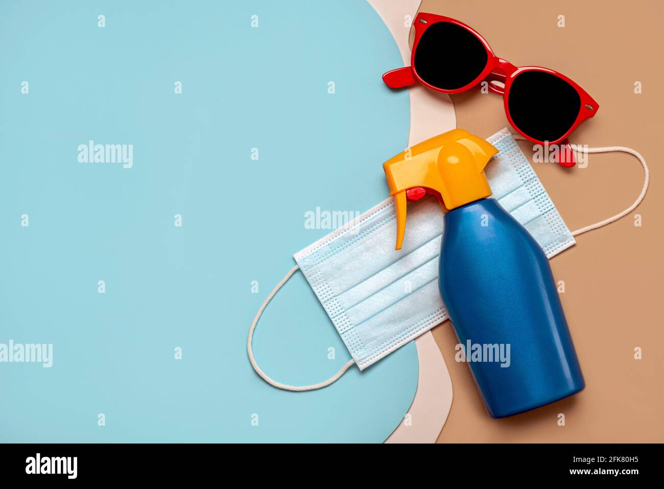 Schützende OP-Maske mit Sonnenbrille und Plastikflasche Sonnenschutzmittel Mit Kopierraum auf buntem Hintergrund.Sommerkonzept mit covid-19 Stockfoto