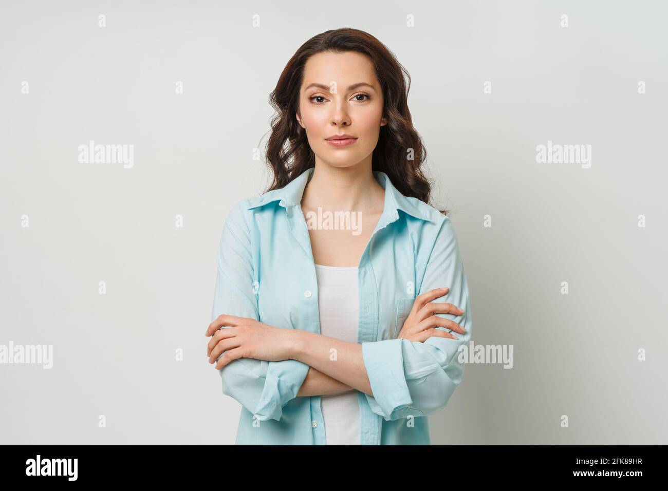 Porträt einer jungen Frau. Liebenswert Brünette in einem Pullover Blick auf die Kamera mit ihren Armen gekreuzt. Stockfoto