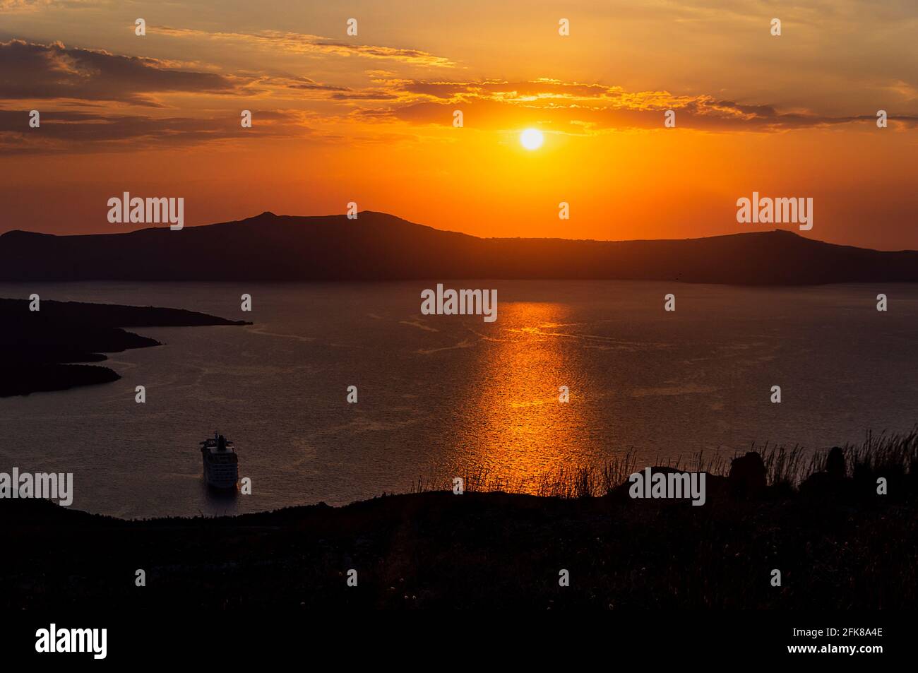 Tolle Abendansicht der Caldera, des Vulkans von Santorini, Griechenland mit Kreuzfahrtschiffen bei Sonnenuntergang. Wolkiger dramatischer Himmel. Stockfoto