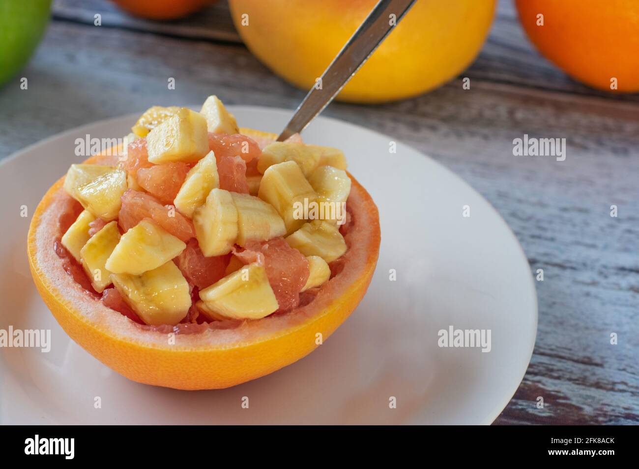 Gesunder Obstsnack mit gehackter Grapefruit und Banane serviert Natürliche Grapefruitschale Stockfoto