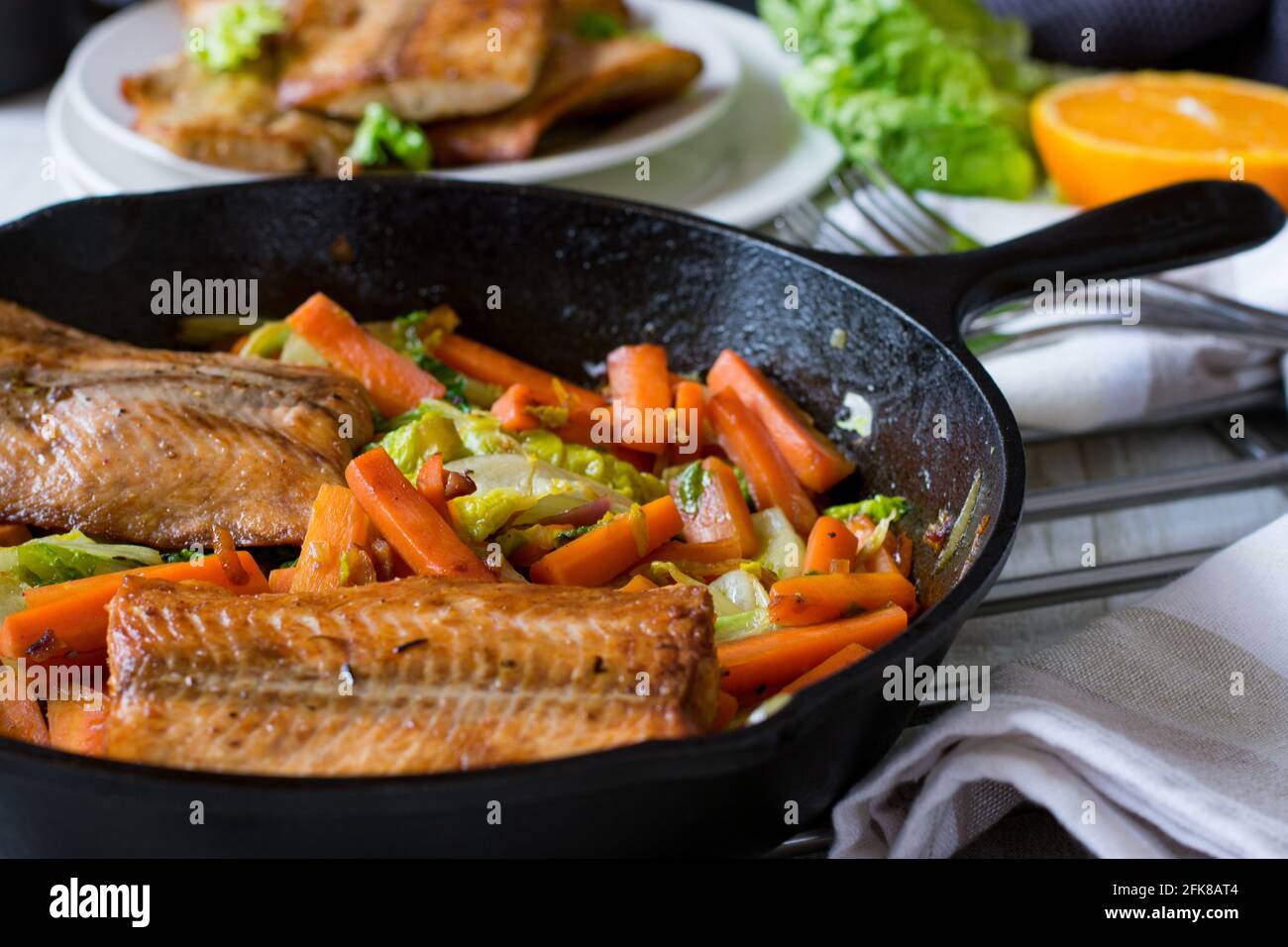 Pfanne mit gebratenen Salomon-Filet und Kohlkarotten-Gemüse Serviert in einer Eisernen Pfanne Stockfoto
