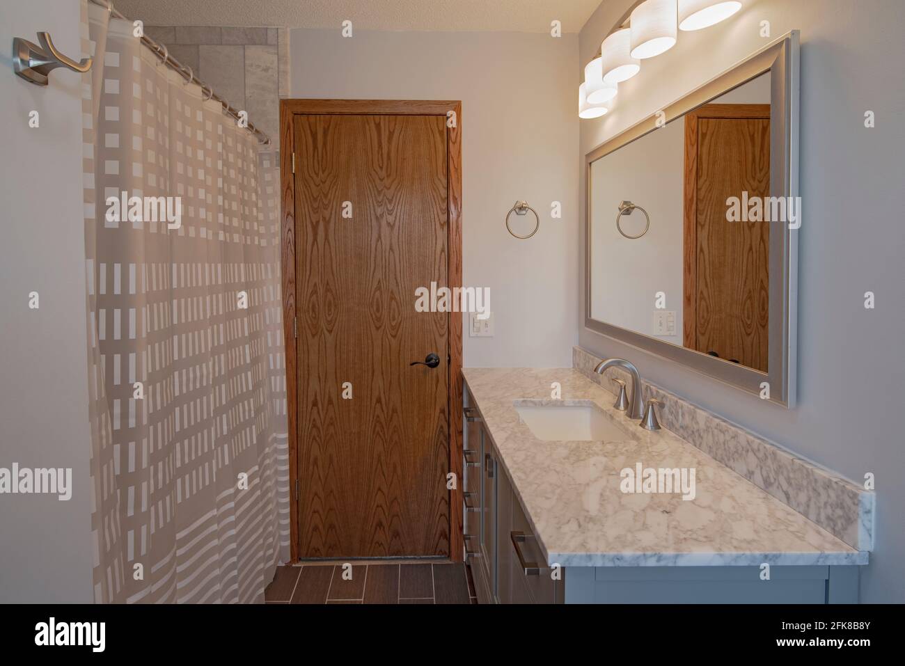 Badezimmer mit Blick auf den Waschtisch, Waschbecken, Spiegelbeleuchtung, Duschvorhang Stockfoto