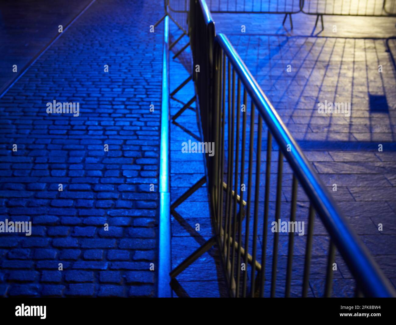 Abstrakte Schnappen eines gentrifizierten Lagerhauses, jetzt Geschäfte und ein Veranstaltungsraum, mit Barrieren, die auf eine abwesende Menge warten. Stockfoto