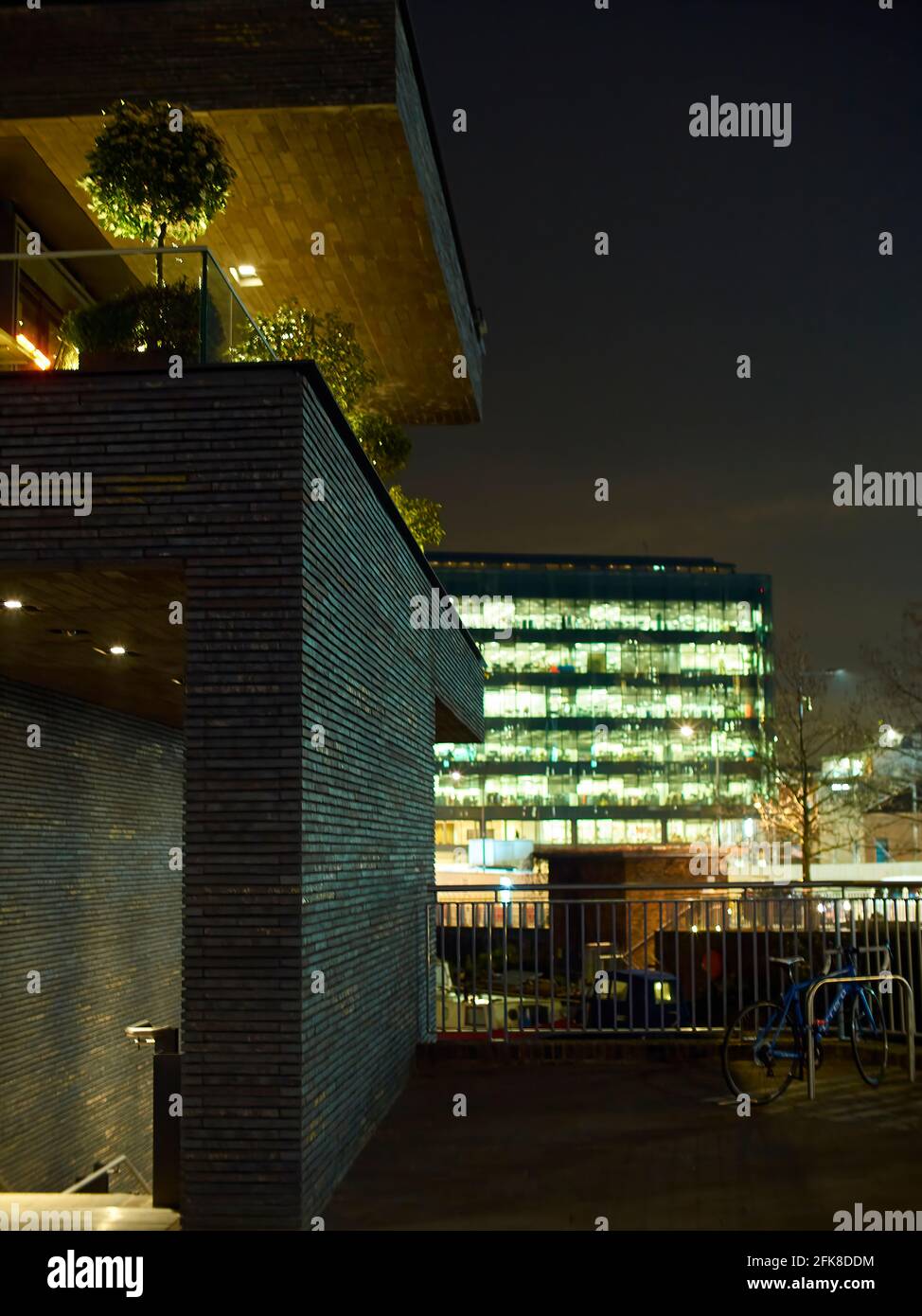Dezenter Blick über den kürzlich umbauten King’s Cross-Bereich bei Nacht, eine Mini-Backsteinmauer und die hellen Lichter eines Kulturzentrums. Stockfoto