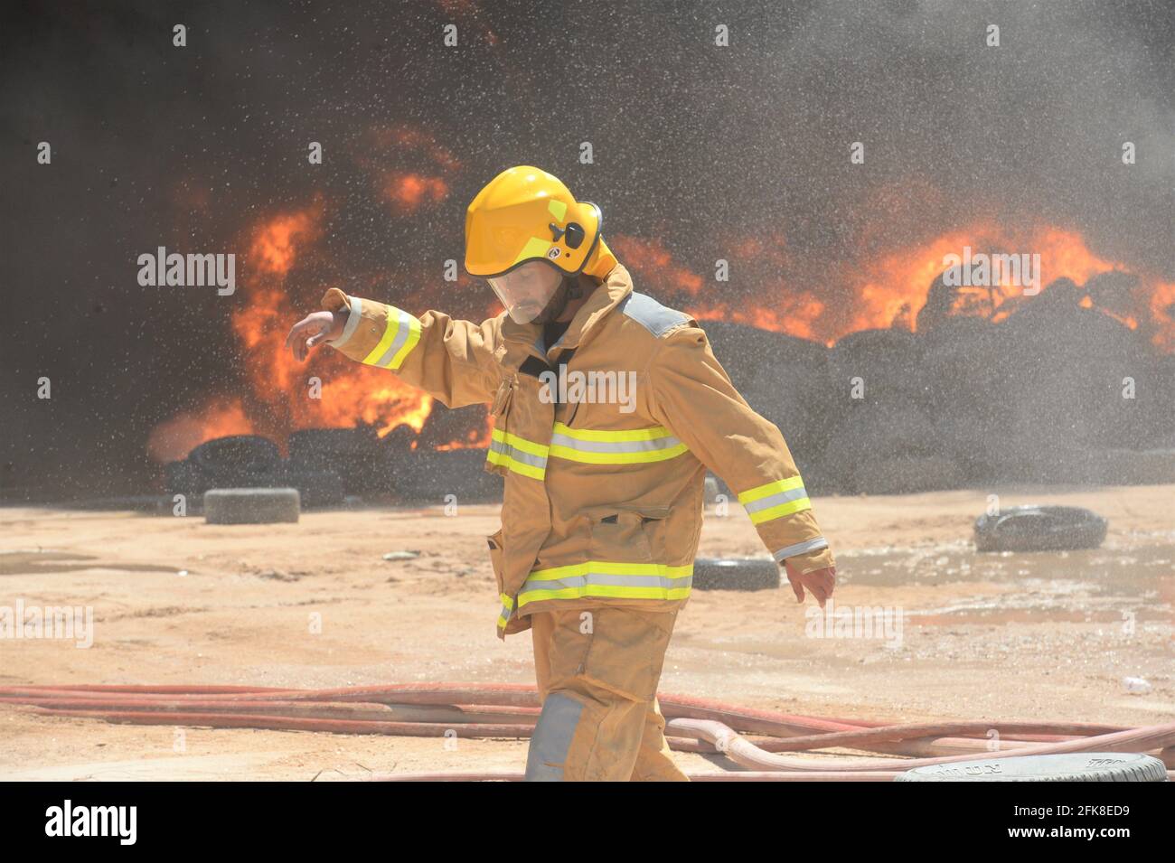 Jahra, Kuwait. April 2021. Ein Feuerwehrmann geht in der Nähe eines Feuerglafens auf einem Reifenhof in Jahra Governorate, Kuwait, 29. April 2021. Am Donnerstag brach auf dem Reifenhof ein Feuer aus, es wurden keine Verletzten gemeldet. Quelle: Asad/Xinhua/Alamy Live News Stockfoto