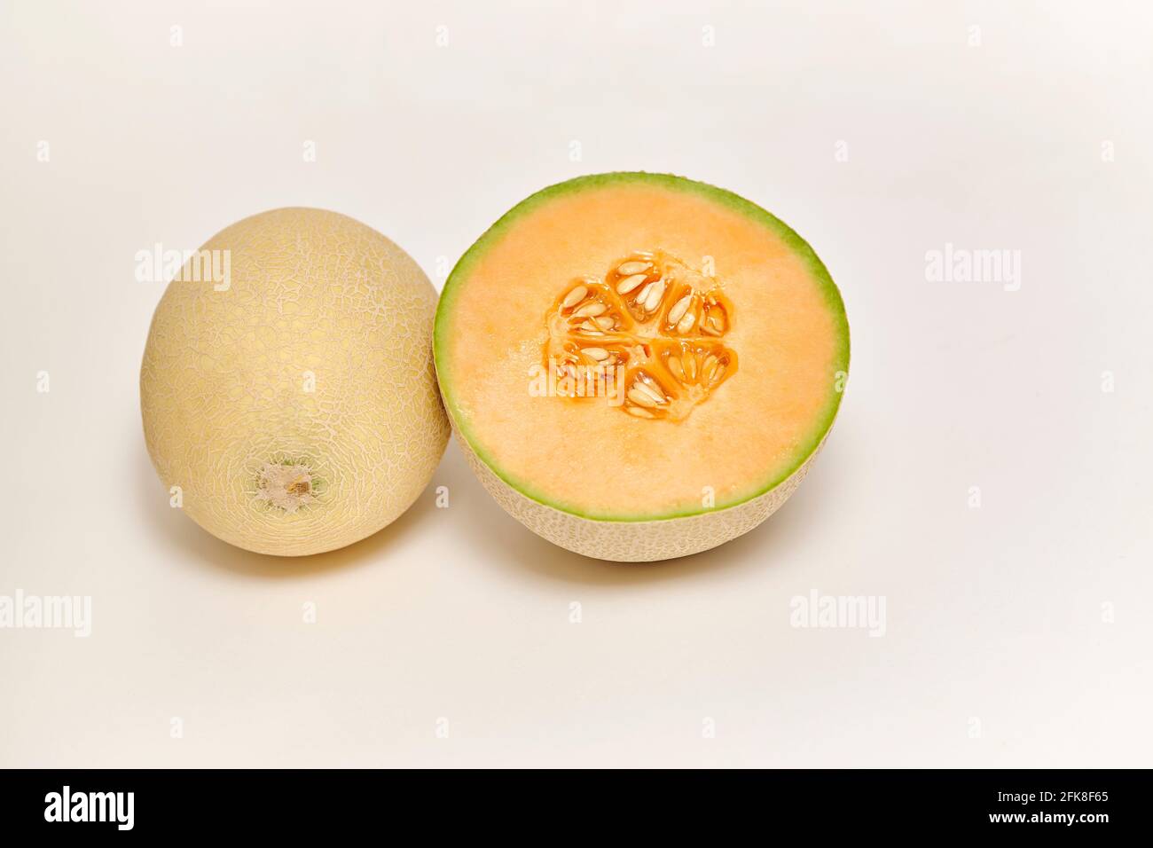 Ganze und geschnittene japanische Melone, Honigmelone oder Cantaloupe (Cucumis melo) auf weißem Hintergrund Stockfoto