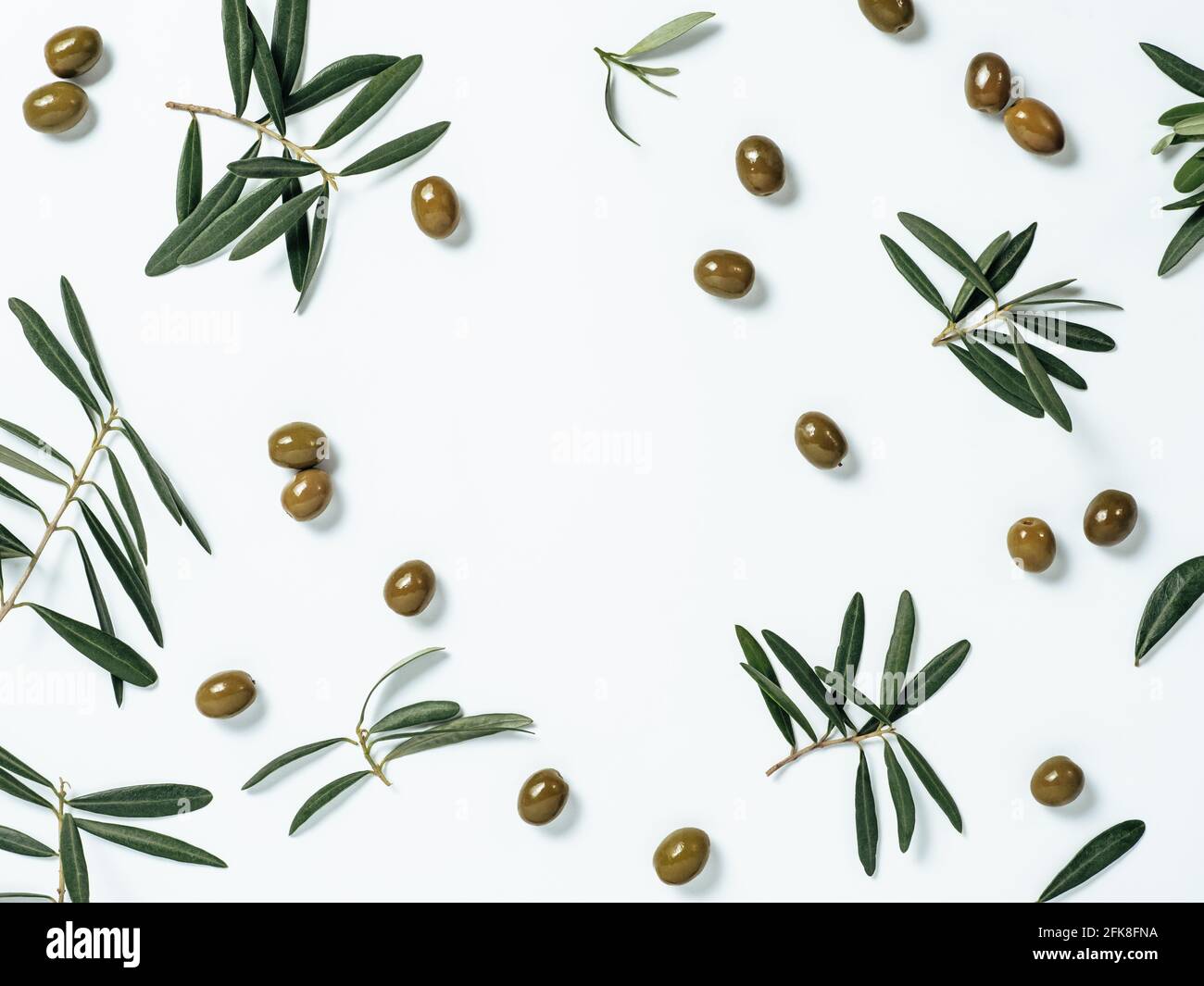 Muster mit grünen Oliven und Oliven Baum Blätter und Zweige auf weißem Hintergrund, kopieren Raum in der Mitte. Olivenbaum Früchte und Äste, Draufsicht oder flache Lage. Stockfoto