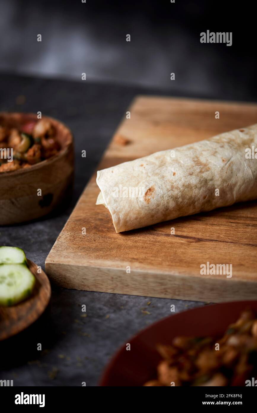 Ein Durum oder Burrito, gefüllt mit Hühnerfleisch, das mit verschiedenen Gemüsesorten wie Zwiebeln oder rotem und grünem Pfeffer sowie frischem Salat und Gurke zubereitet wird, Stockfoto