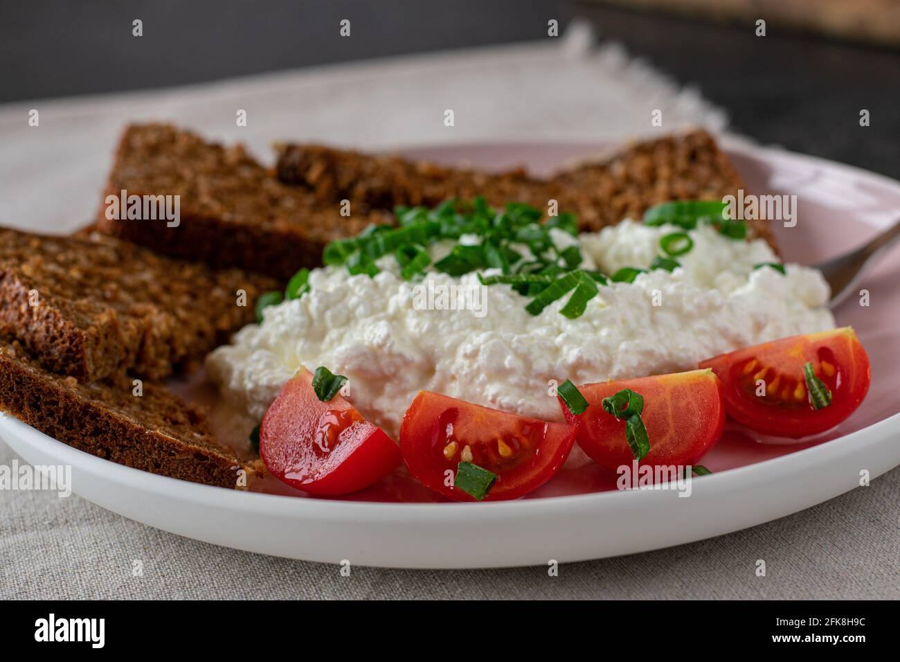 Gesunde Mahlzeit mit Vollkornbrot, Quark und Tomaten auf einem Teller serviert Stockfoto