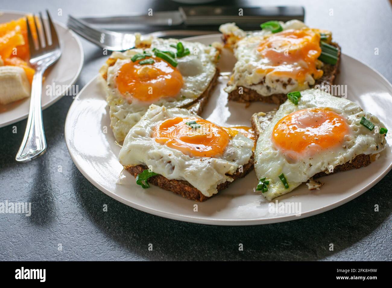 Ein Teller mit offenen Sandwiches und frisch gebratenen Sandwiches Eier und Schnittlauch isoliert auf einem Tisch zu Hause Stockfoto