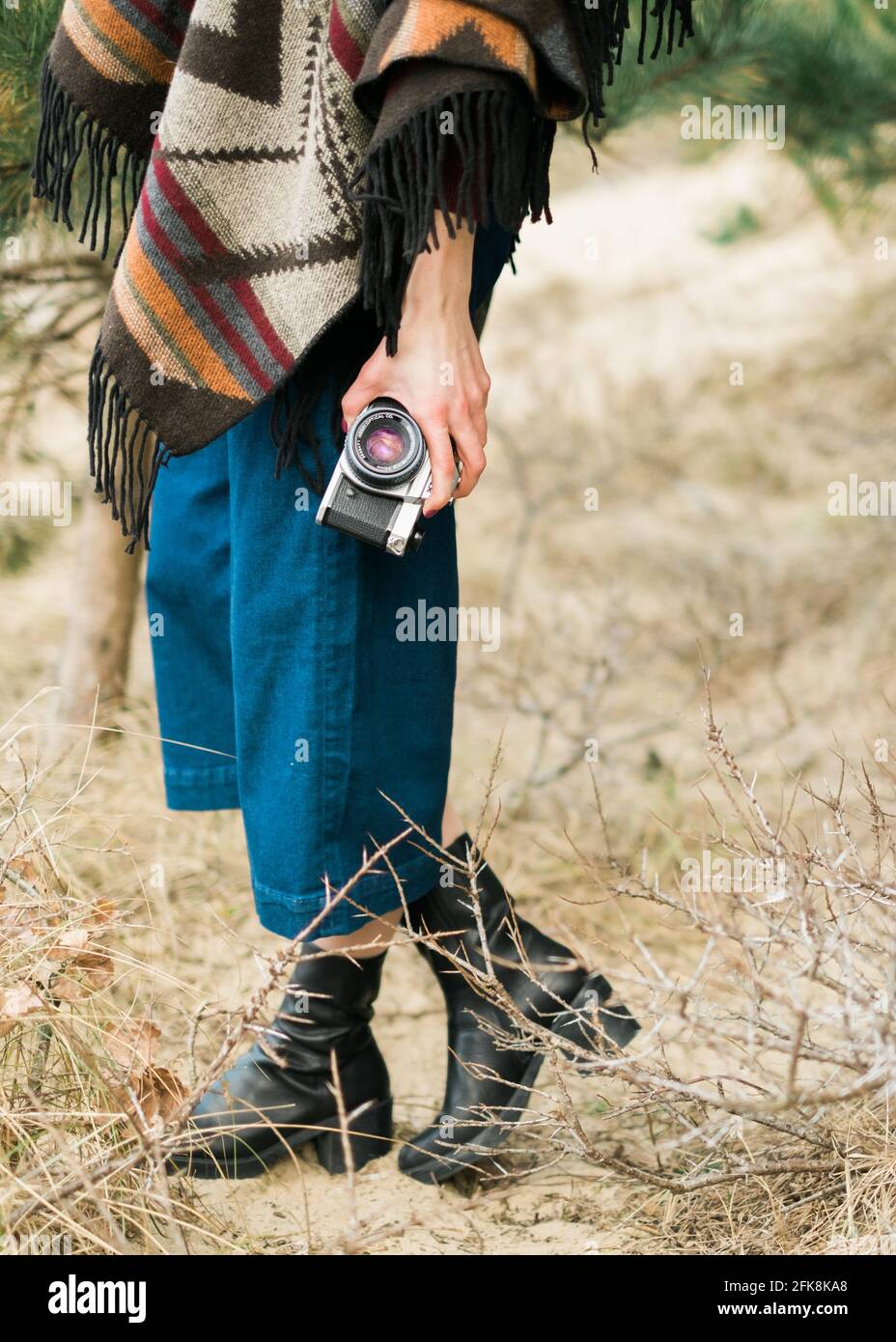 Junge Frau, die in einem Wald mit einer Vintage-Kamera fotografiert. Kinfolk-/Outdoor-Stil. Stockfoto