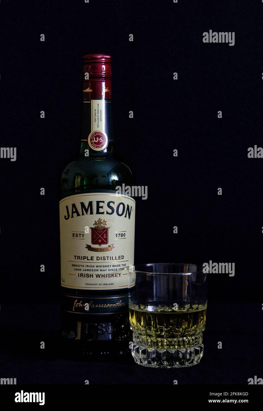 Kristallglas und Flasche mit schwarzem Jameson Whiskey Hintergrund Stockfoto