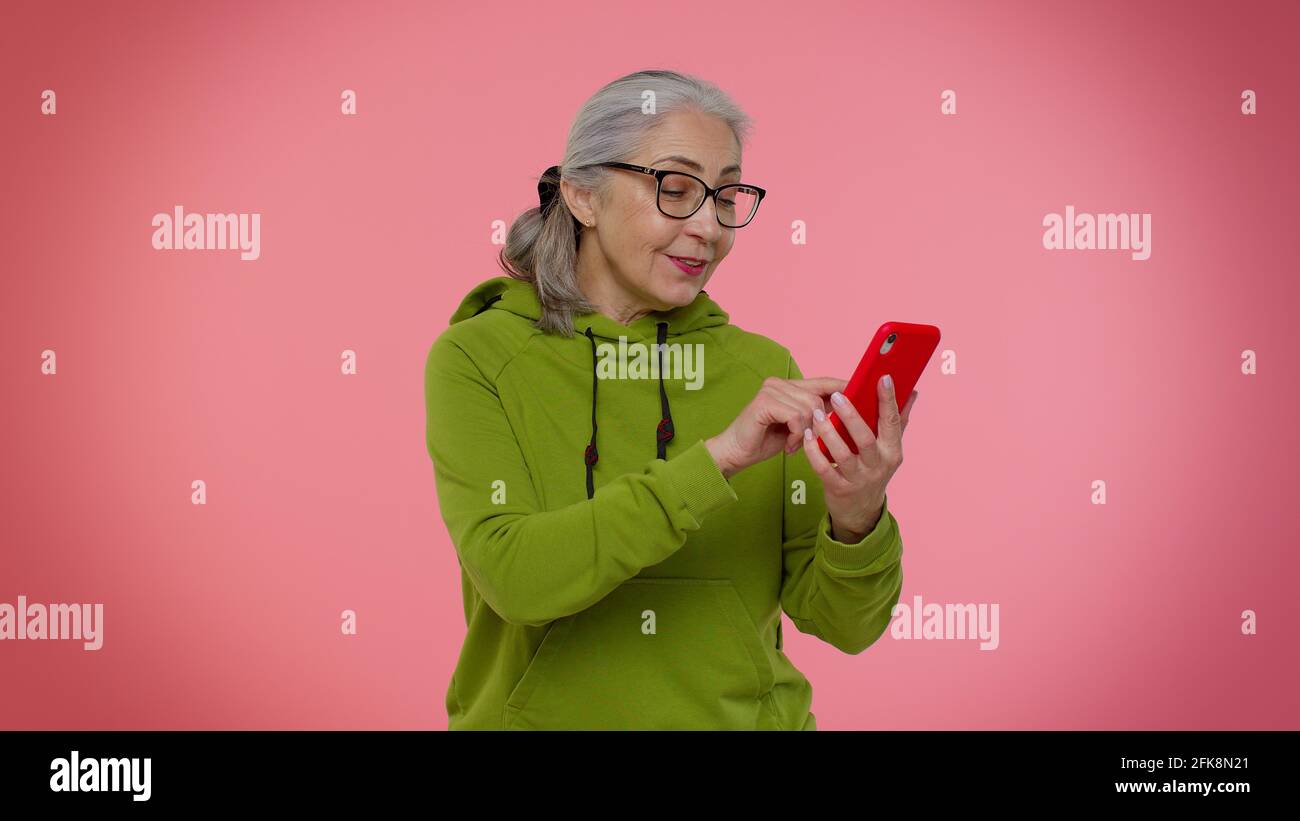 Ältere alte Oma Frau mit Mobiltelefon Eingabe neuer Post, sms-Nachricht, Surfen, soziale Netzwerke Stockfoto