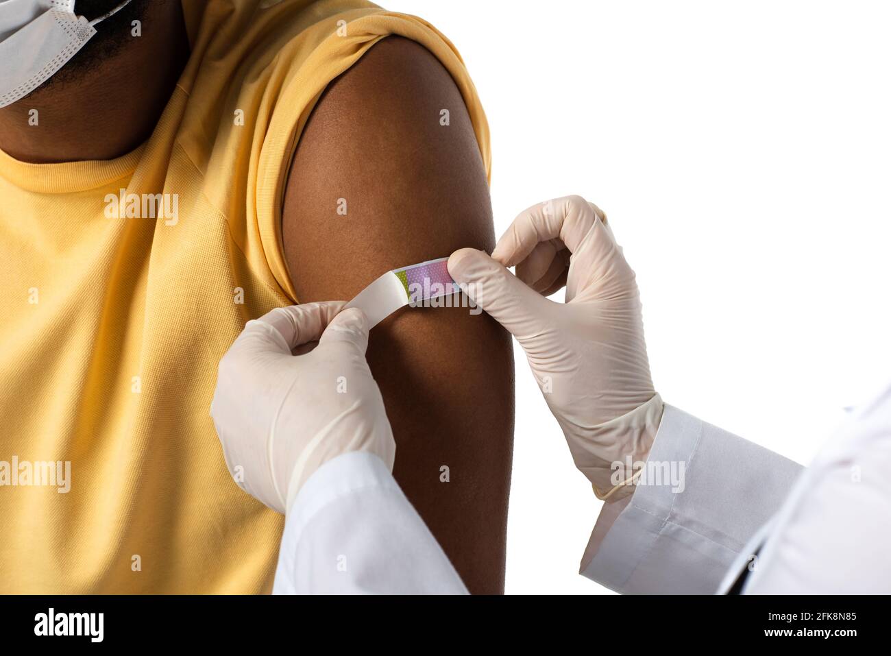 Beschnittene Ansicht des Arztes, der Klebstoffputz auf den Arm des afroamerikanischer Patient isoliert auf Weiß Stockfoto