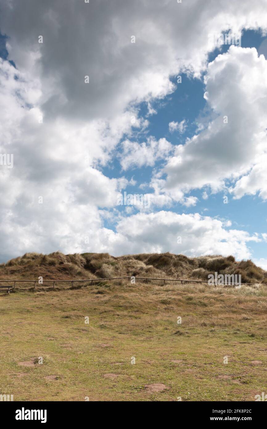 Ein grasbewachsener Hügel an der Südküste Englands mit Ein blauer Himmel und eine dramatische Wolkenbedeckung Stockfoto