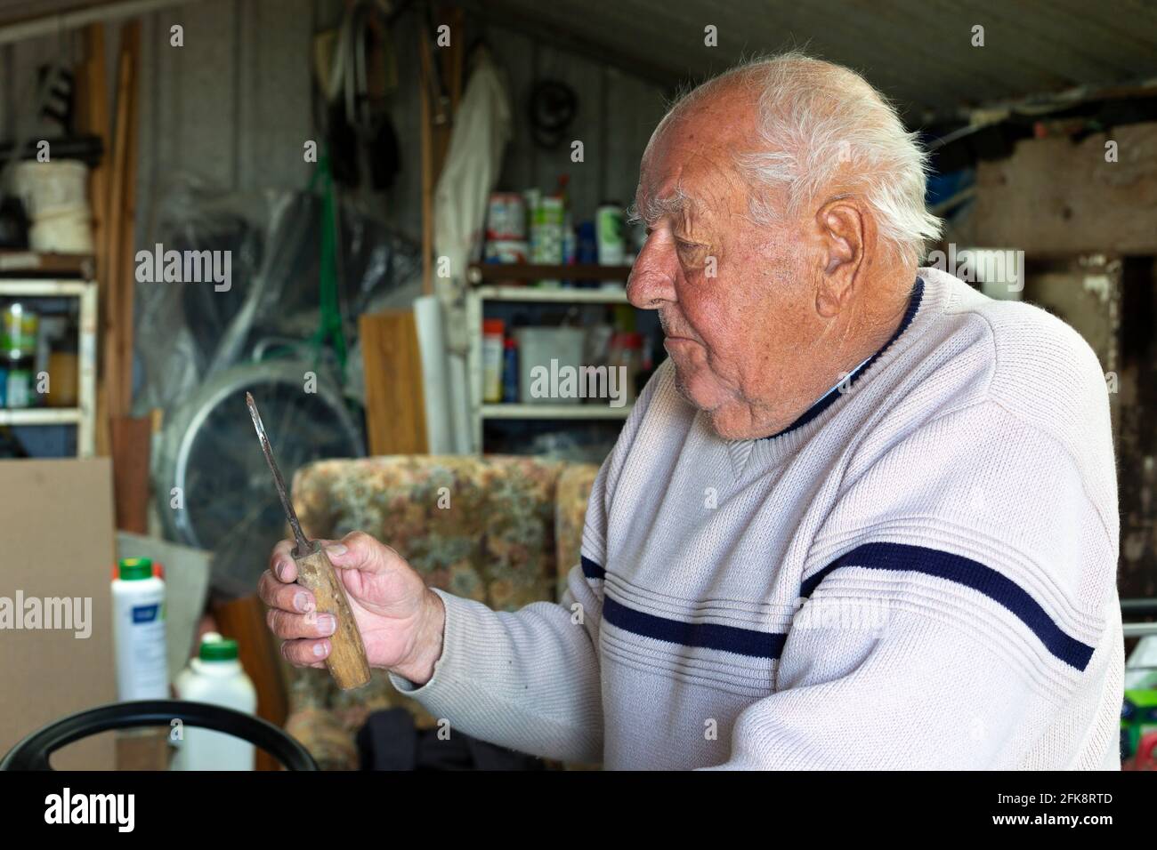 Älterer Mann im Schuppen, der altes Werkzeug ansieht Stockfoto