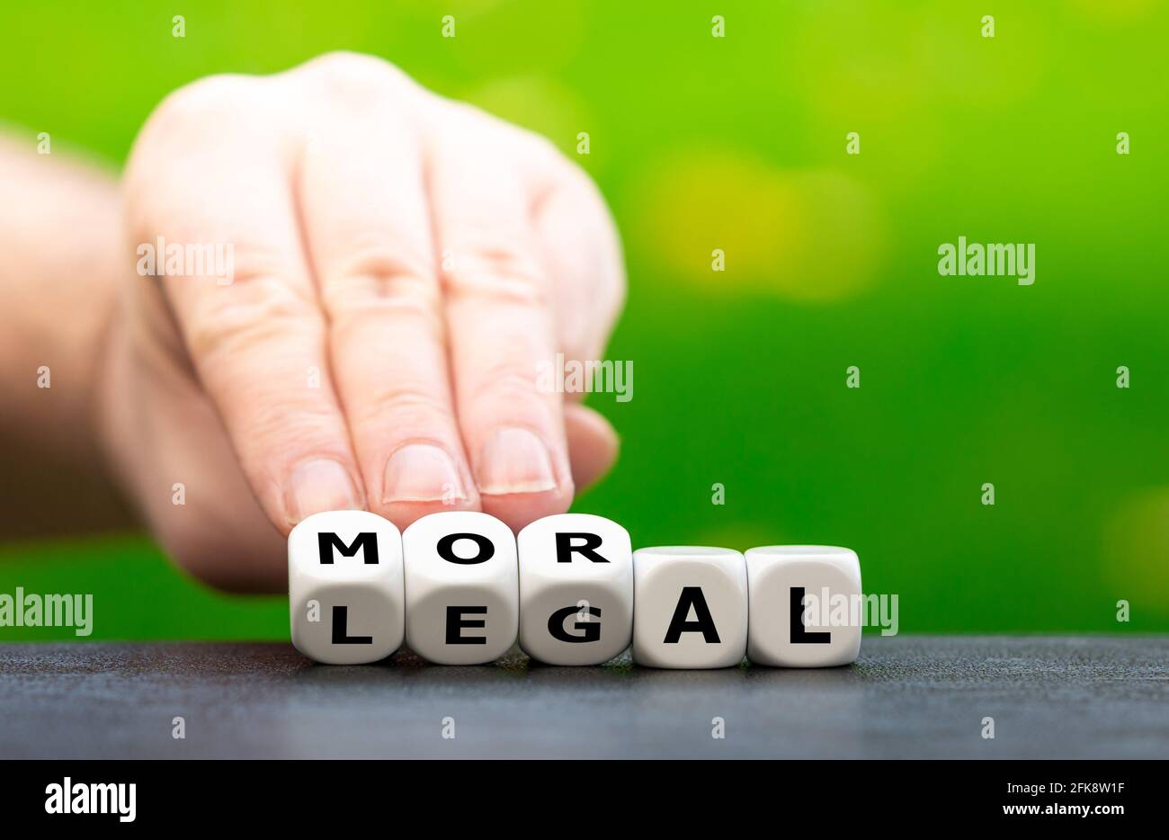 Die Hand dreht Würfel und ändert das Wort „legal“ in „oral“. Stockfoto